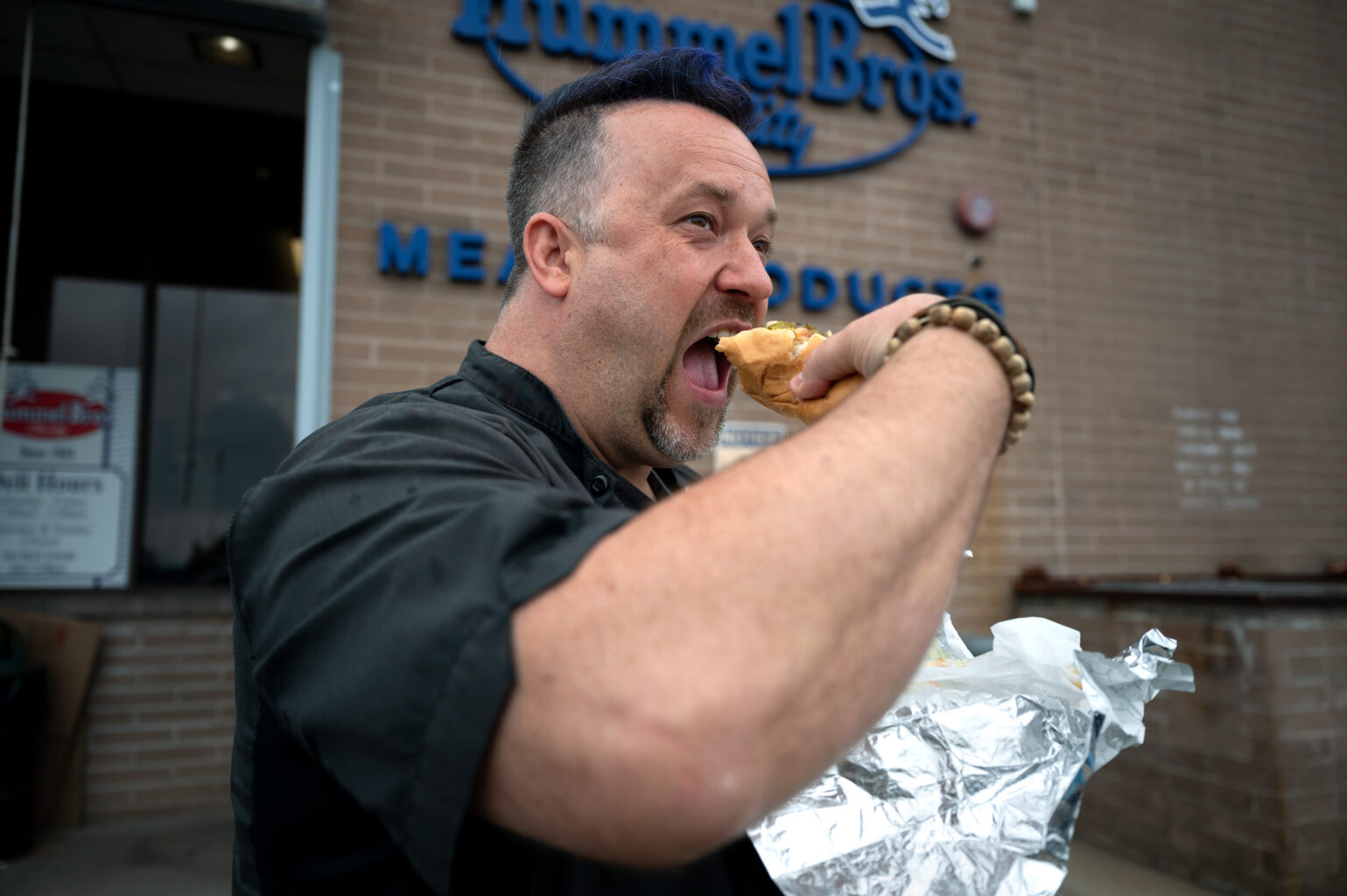 “Seasoned” host Chef Plum digs into a fresh dog after a tour of the Hummel Bros. Hot Dog factory in New Haven, Conn. 